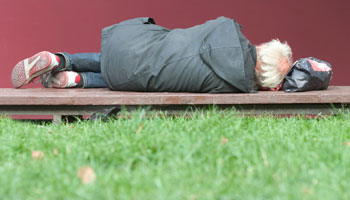 Man experiencing homelessness sleeping on the ground