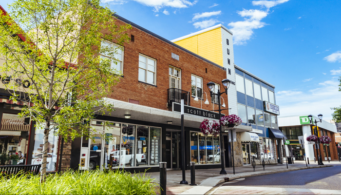 A summer photo along little Gaetz Avenue featuring the Scott Block Theatre and the Bunn Building