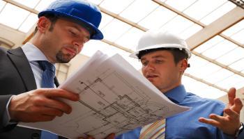 Two men in hard hats looking at blueprints