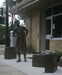 Bronze representation of Julietta Sorensen surrounded by three bronze suitcases.
