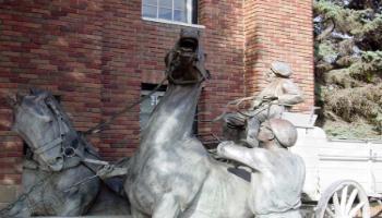 Close up of the front of the bronze sculpture of a horse-drawn wagon used by the fire brigade.