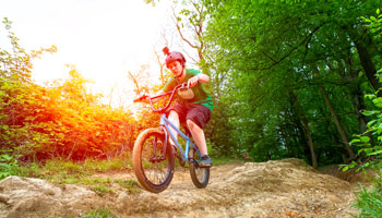 photo of teenage boy riding BMX bike in a treed area